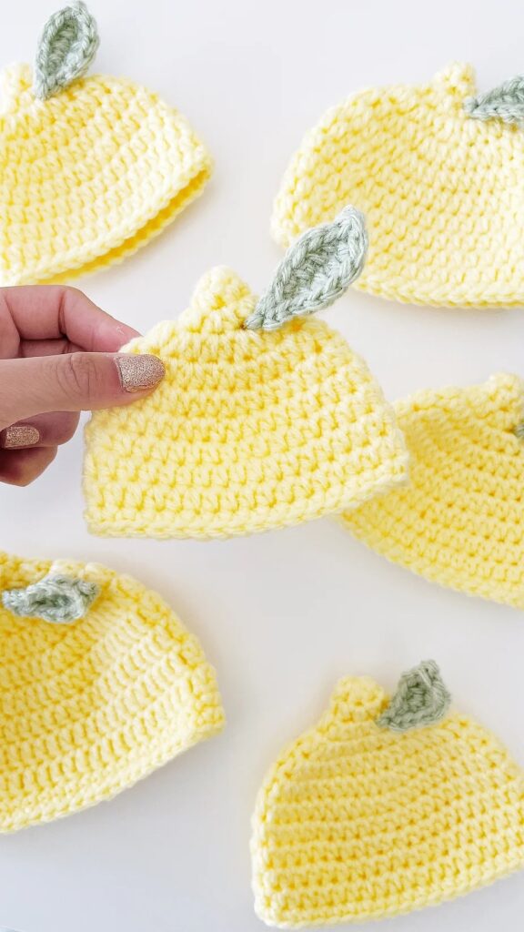 Cute yellow infant crochet hat patterns styled like lemons, complete with green leaves