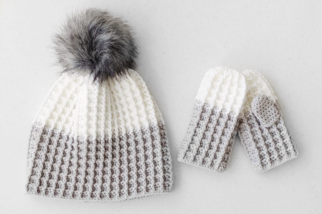 Stylish infant crochet hat patterns featuring a matching hat and mittens with a fur pompom.
