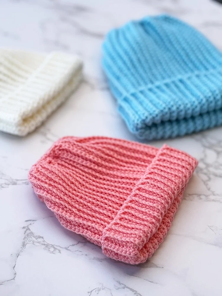 Three cozy infant crochet hat patterns in pastel colors, perfect for adding warmth to your little one's outfit.