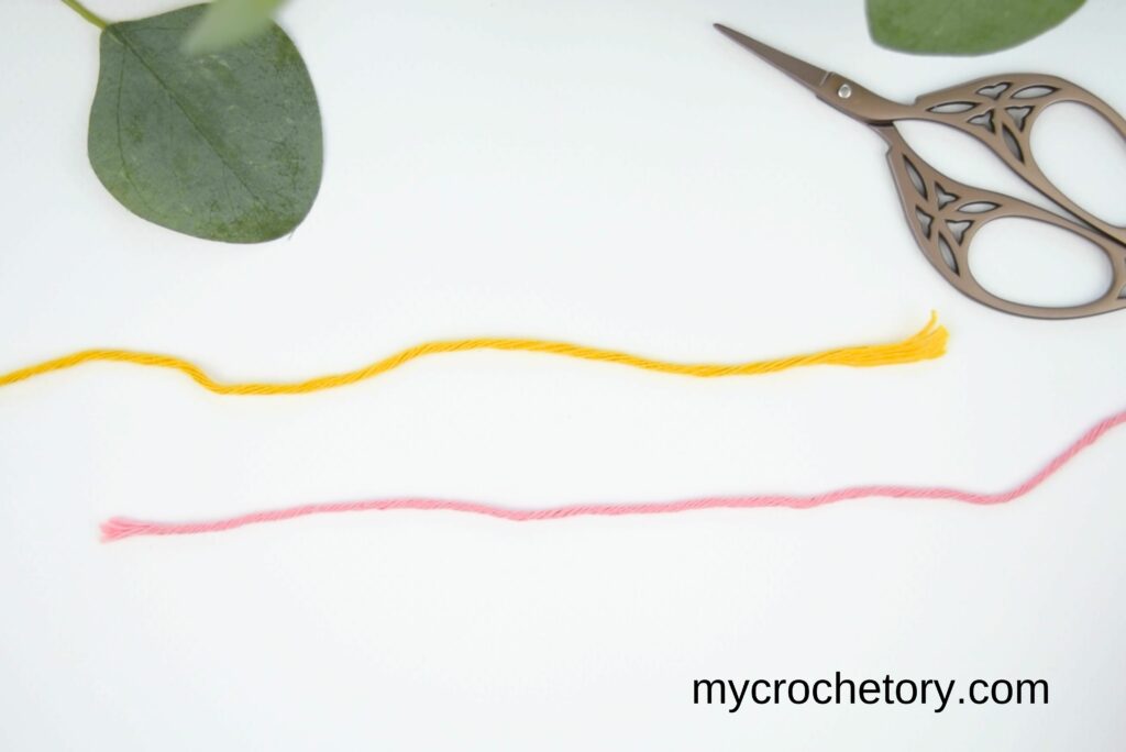 Two yarn strands laid out to start the magic knot for joining yarn.