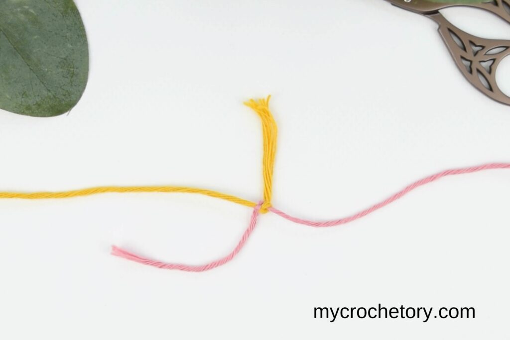 Final step of pulling the working yarn to tighten both knots and complete the magic knot for joining yarn.