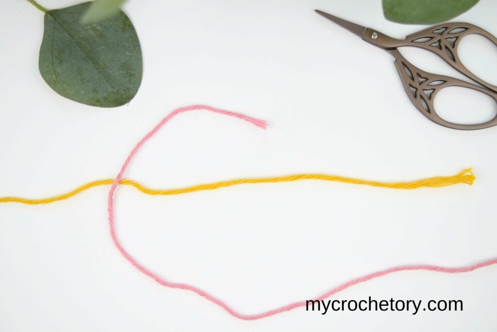 First step of the magic knot for joining yarn, crossing two yarn strands.