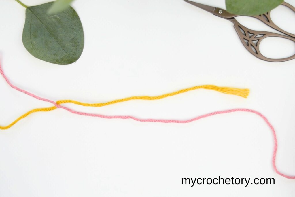 Yarn strands pulled tight to secure the magic knot for joining yarn."