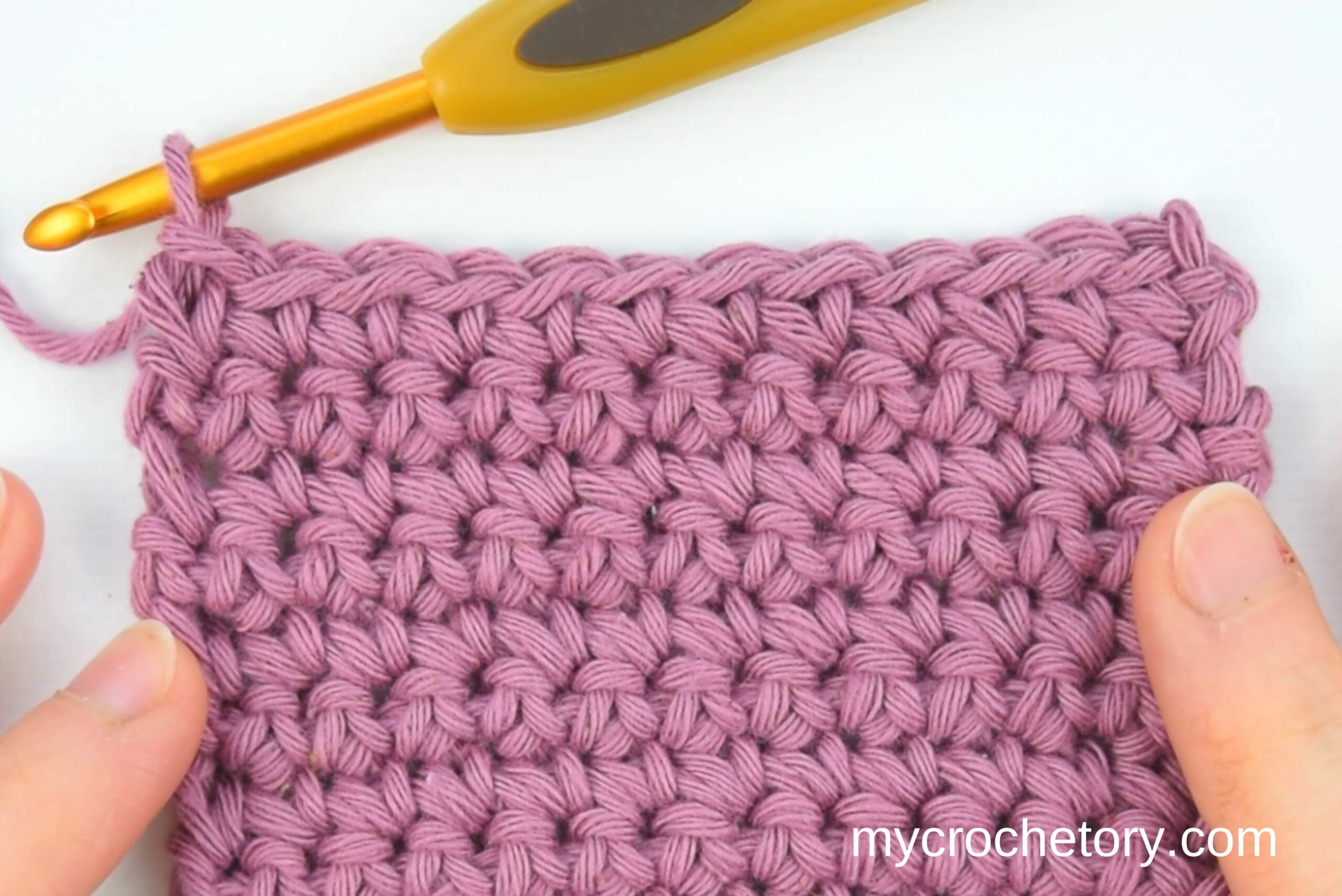 Pink single crochet swatch with a gold crochet hook, one of the crochet stitches for beginners