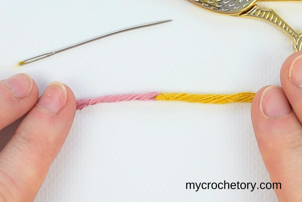 A smooth and secure connection between pink and yellow yarn, showing how to join yarn ends.