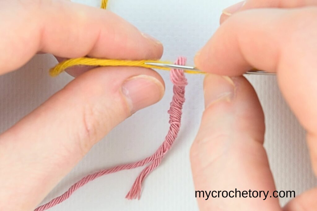 A needle weaving through second yarn strands, a key step in how to join yarn ends.
