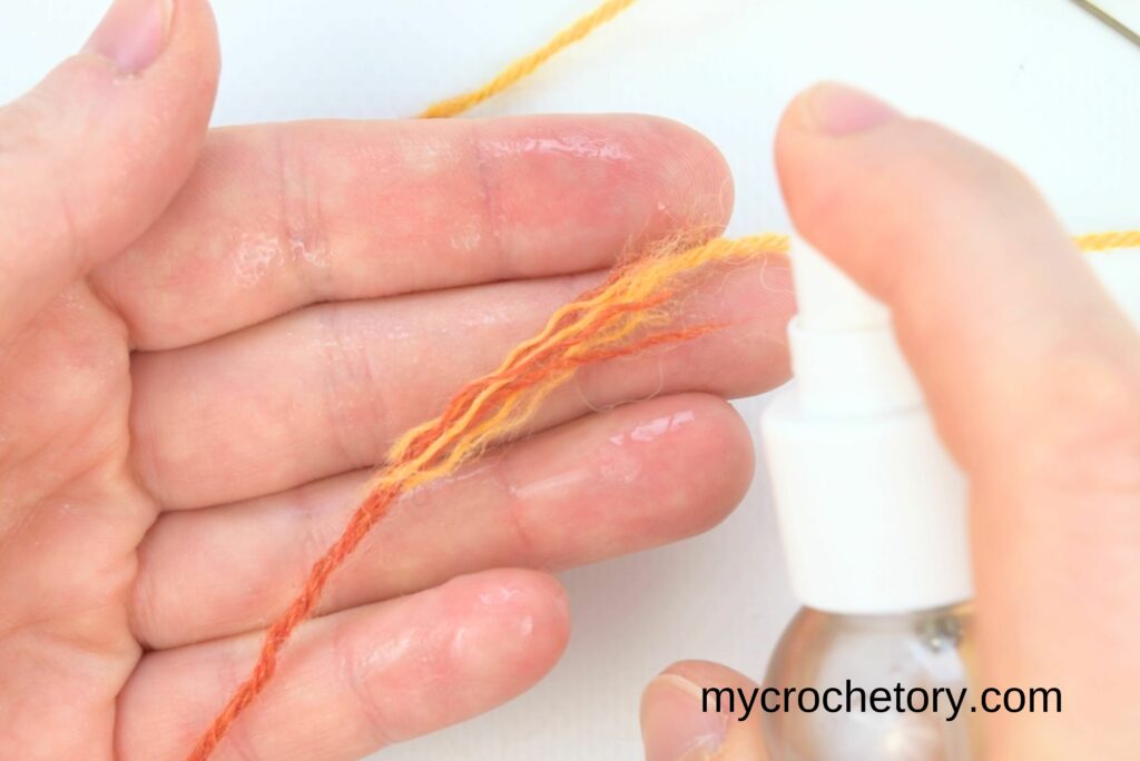 Spraying water on yarn ends to prepare them for rubbing together in how to join yarn ends.