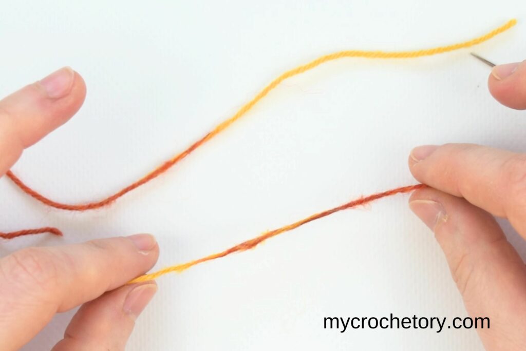 A smooth, seamless join between orange and yellow yarn, showing the result of how to join yarn ends.