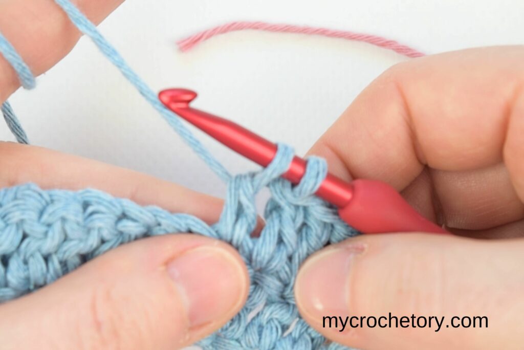 Finishing a stitch with blue yarn, ready to join new yarn in how to join yarn ends.