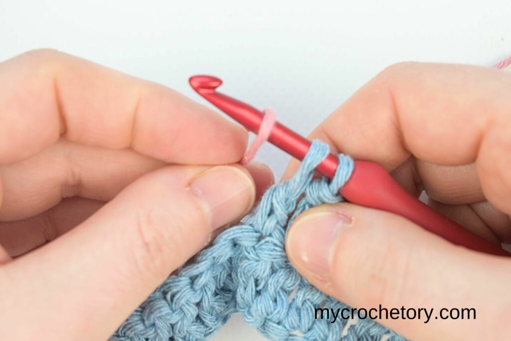 A pink yarn loop added to the crochet hook for how to join yarn ends.