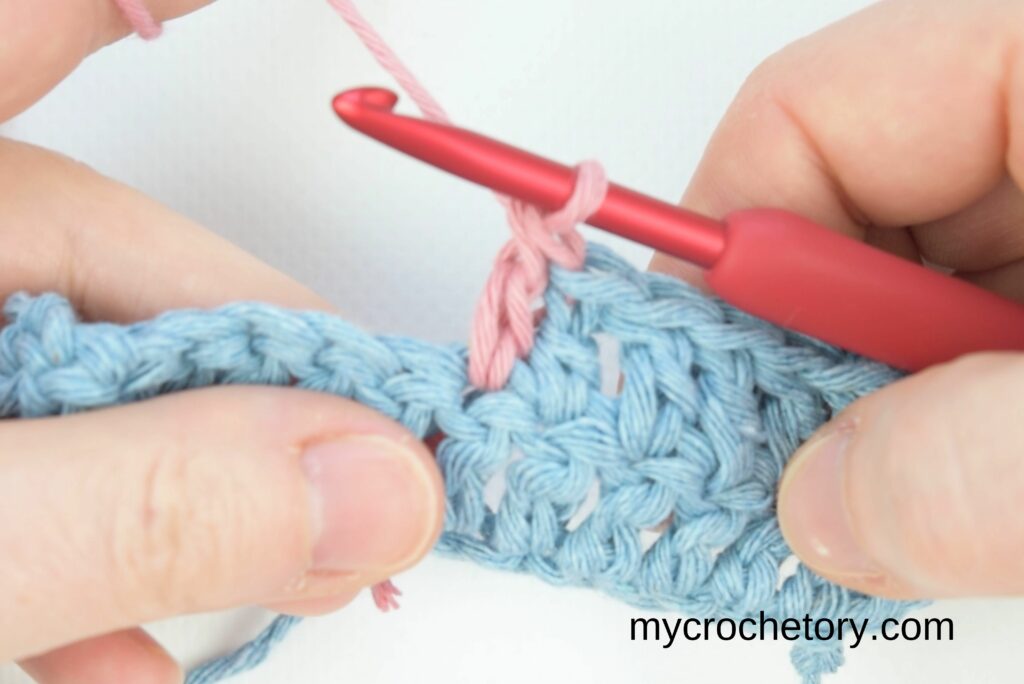 Continuing crochet with pink yarn after joining, showing how to join yarn ends.