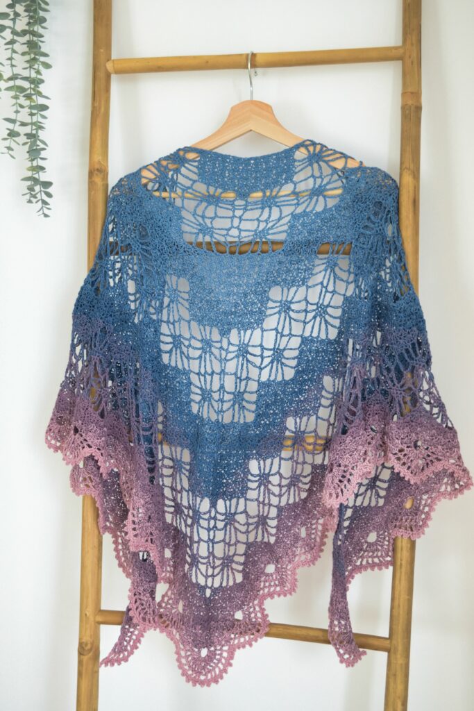Arys Shawl, a lace triangle crochet shawl, hanging on a ladder