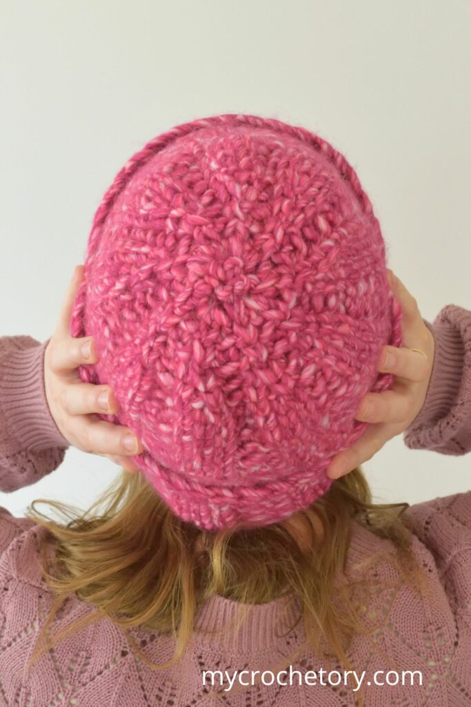 Back view of a pink chunky crochet hat showing the crown stitches.