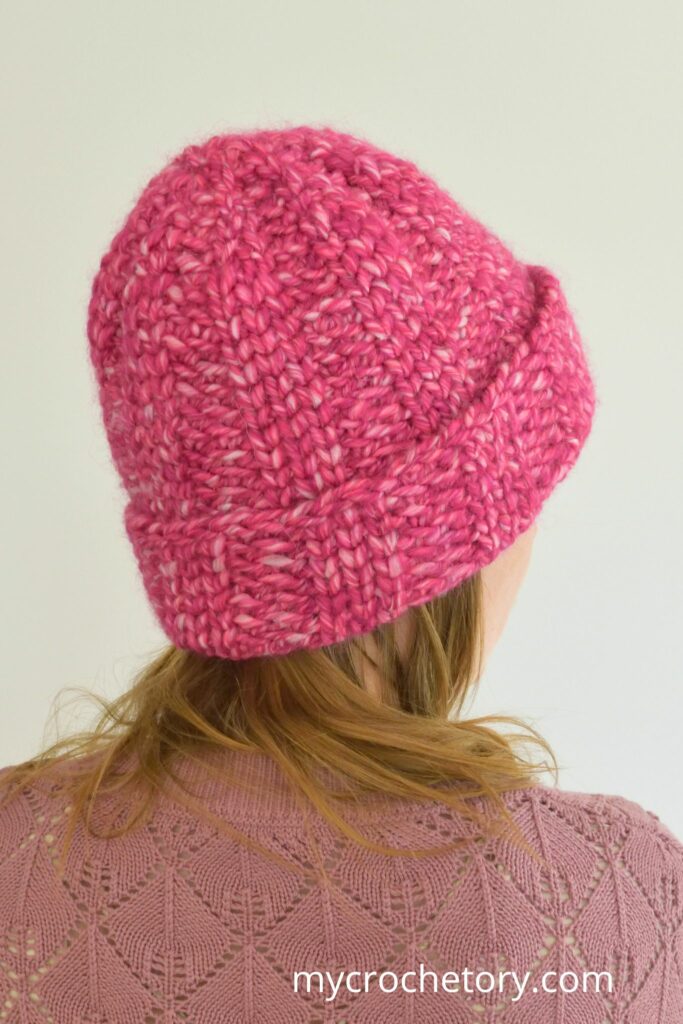 Rear view of a pink crochet hat with textured stitches and folded brim.