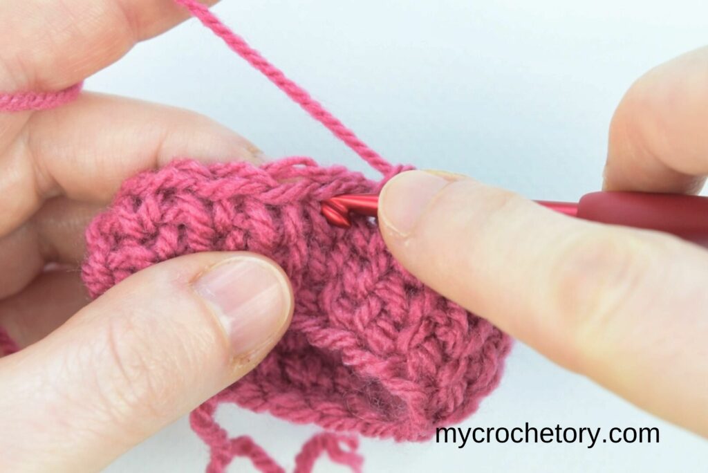 Beginning decrease method 2 in the crochet waistcoat stitch by inserting the hook into the first stitch.