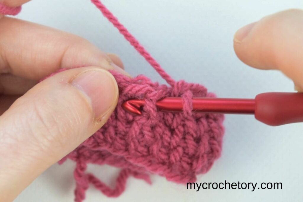 Midway through decrease method 2 in the crochet waistcoat stitch with multiple loops on the hook.