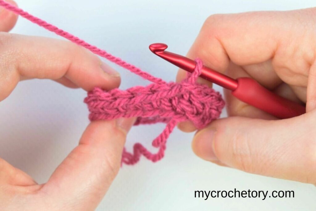 Close-up of the first round of single crochet stitches in pink yarn, demonstrating the base for the crochet waistcoat stitch.