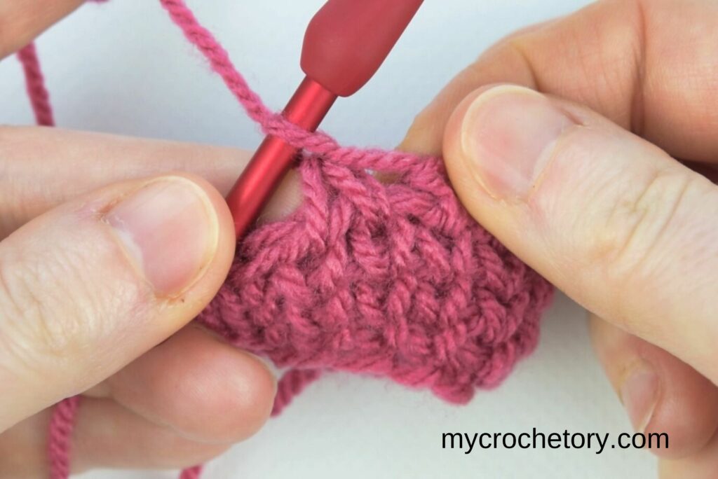 Completing decrease method 1 in the crochet waistcoat stitch by pulling through all loops for a smooth finish.