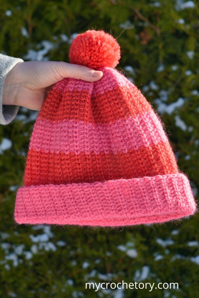 Holding up a finished beanie made from this fast crochet hat pattern, featuring a stretchy design.