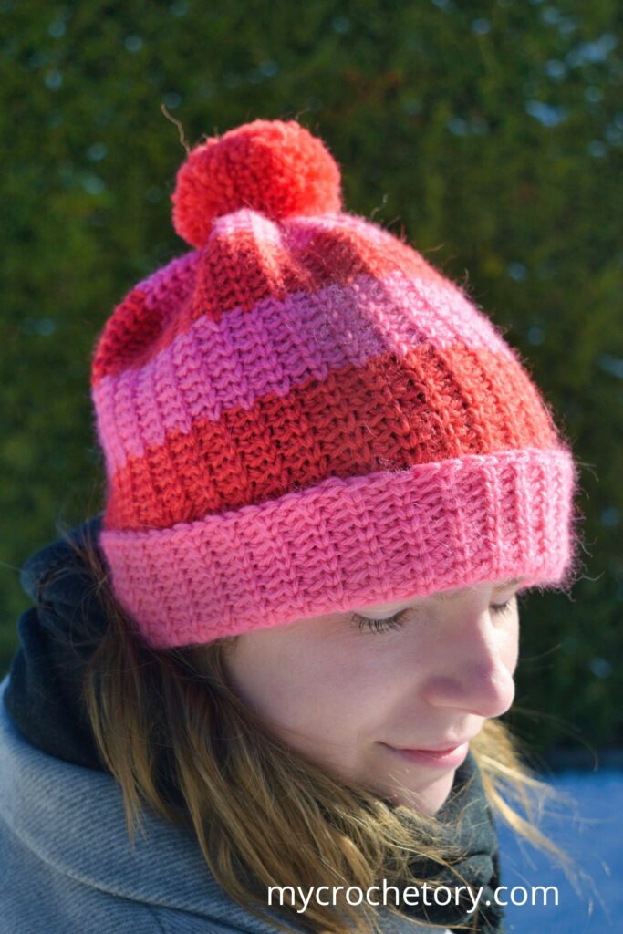 The Fleur de Stripe Hat, a warm fast crochet hat pattern, shown from the back with a pom-pom.