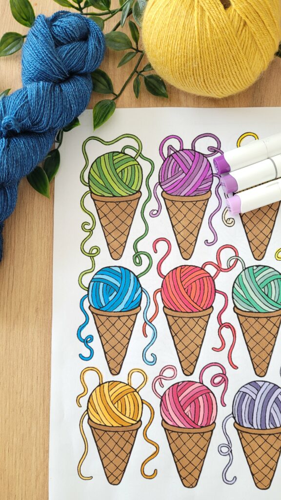 Colorful yarn-in-ice-cream-cones page from a crochet coloring book with marker caps resting on top.
