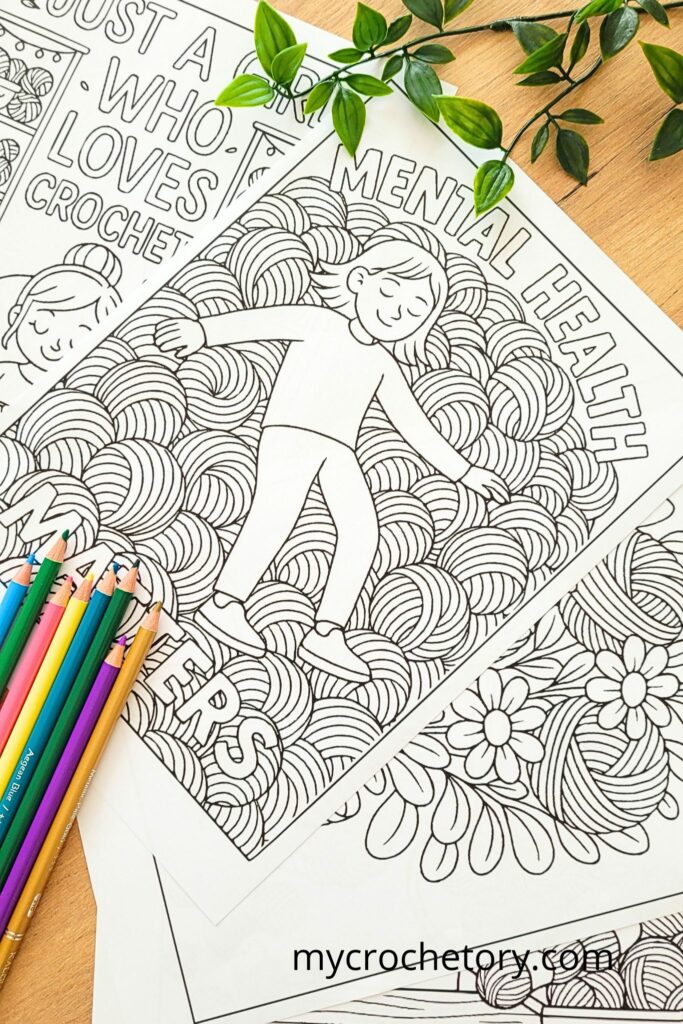 Several black-and-white crochet coloring book pages featuring yarn balls and motivational designs, stacked with colored pencils.