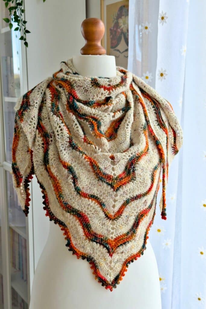 The Norra boho shawl crochet pattern wrapped on a mannequin, showing lace waves and autumn colors.