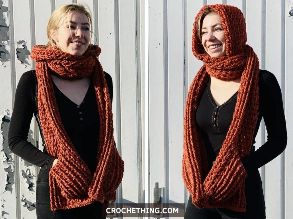 Woman wearing a long orange crochet hooded pocket shawl with deep pockets, made using feather stitch for cozy texture.