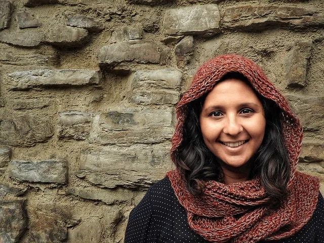 Woman wearing a rust-colored crochet hooded scarf with subtle texture, handmade for a cozy fall look.
