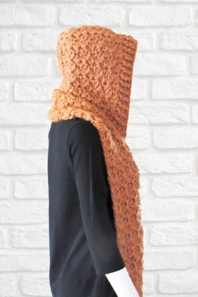 Side view of a chunky crochet hooded scarf in caramel yarn, made with thick textured stitches for extra warmth and comfort.