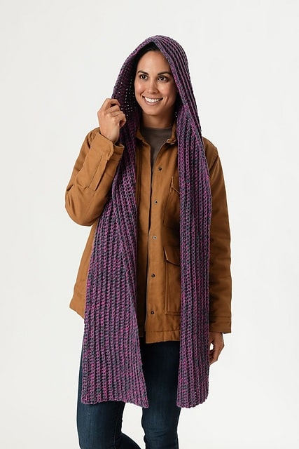 Smiling woman wearing a long crochet hooded scarf in purple and black marled yarn, great for layering.