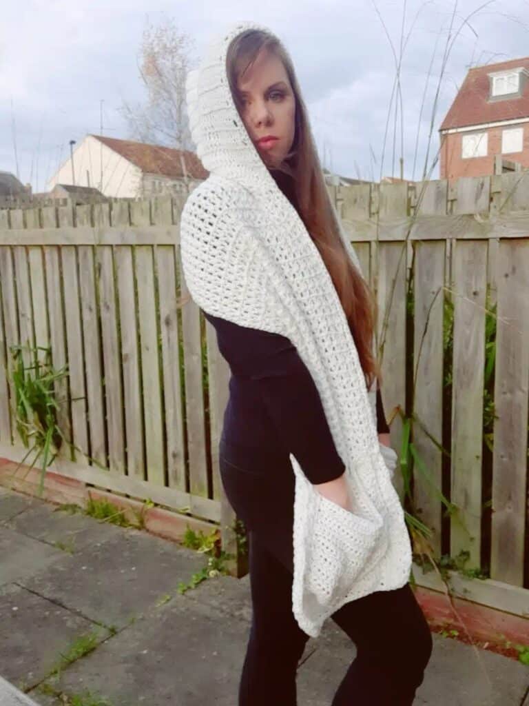 Woman in white crochet hooded shawl with large pockets, perfect for a lightweight and elegant handmade wrap.
