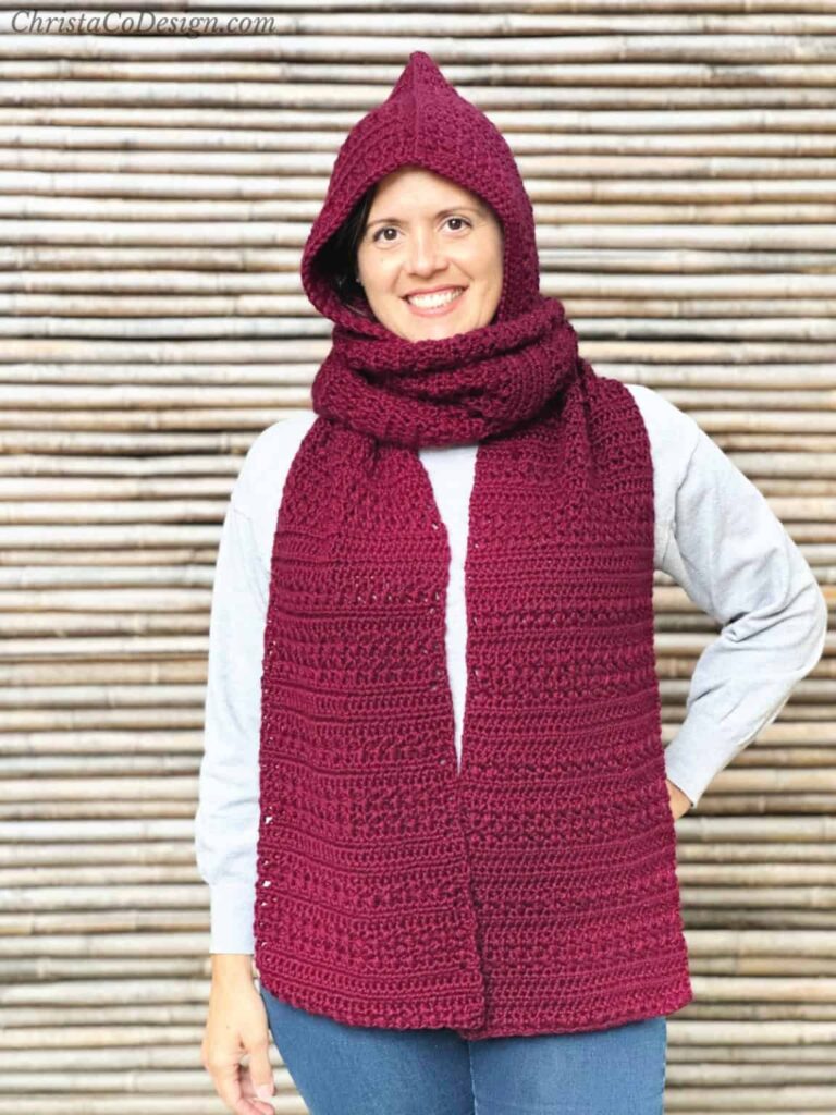 Woman wearing a burgundy crochet hooded scarf with rich texture and a pointed hood, handmade for cozy winter style.