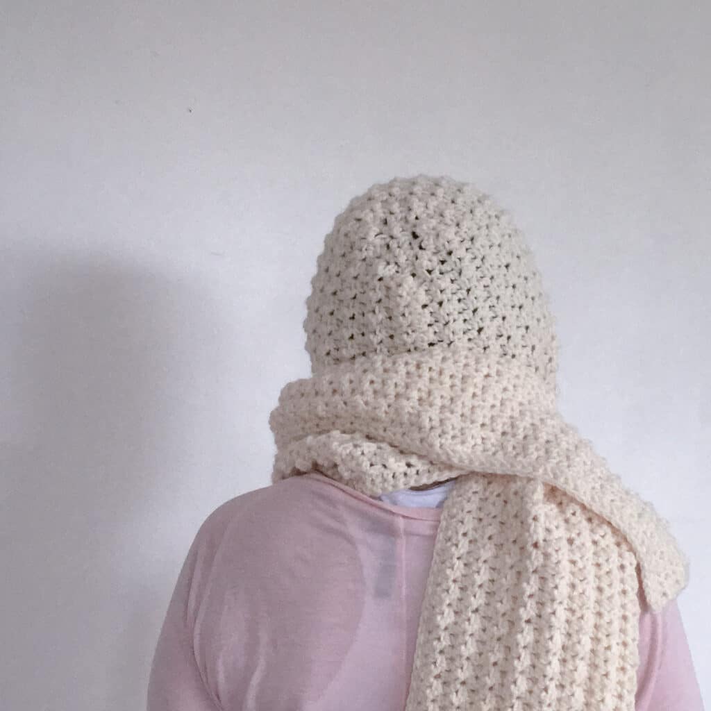 Cream crochet hooded scarf shown from behind, made with textured stitches for a warm and minimalist winter look.