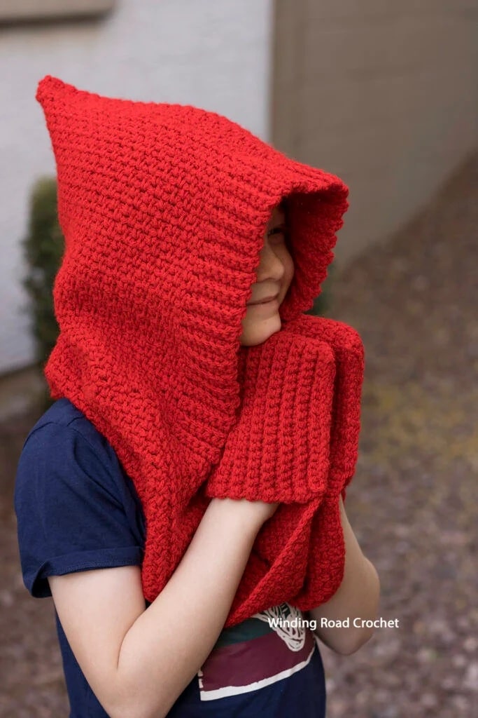 Child wearing a bright red crochet hooded scarf, warm and perfect for winter days.