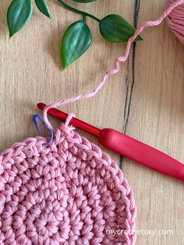 Crocheting a circle in the round with stitch marker, showing correct stitch placement and even increases for a flat result