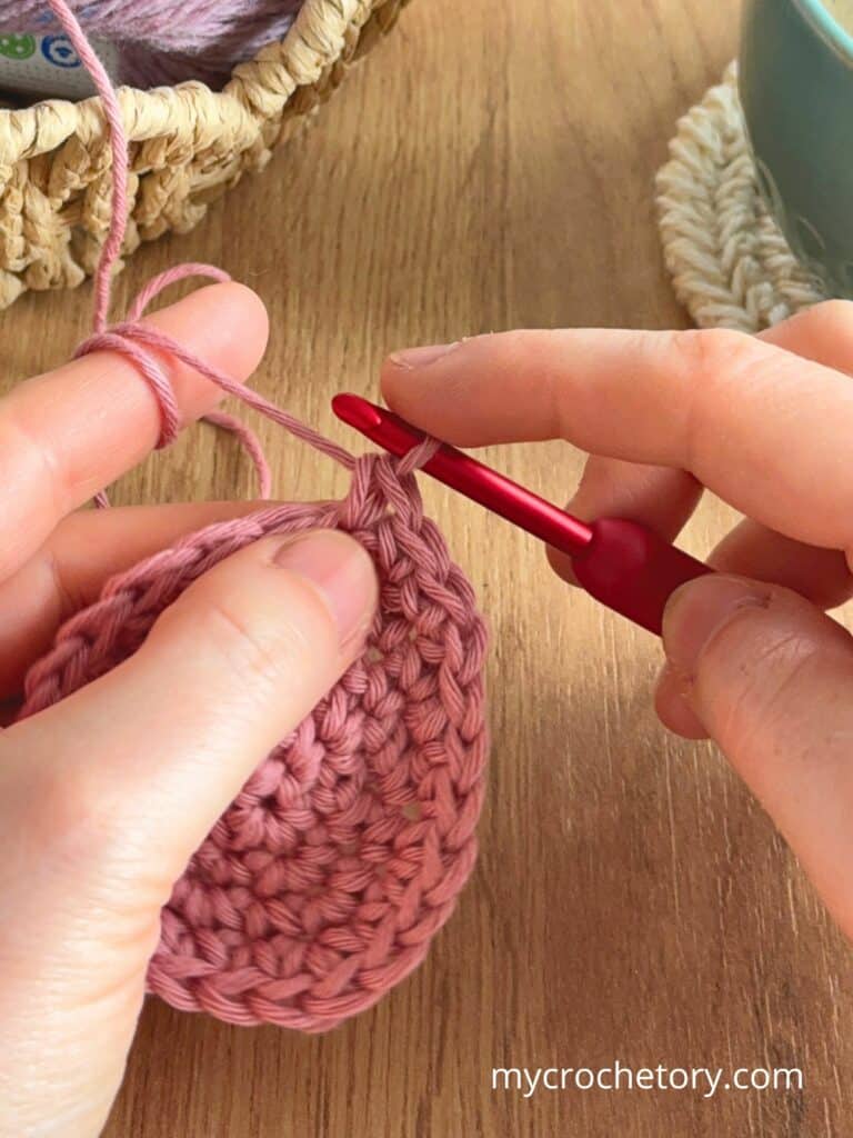 Close-up of crocheting a circle in the round, showing stitch placement and tension while working the next round