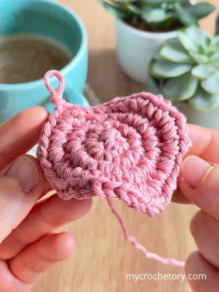 Crochet circle curling upward instead of lying flat, showing a common issue caused by tight tension or missing increases