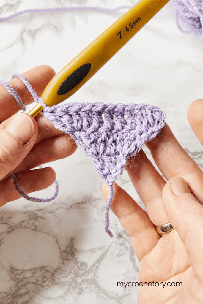 Small bottom up crochet triangle shawl showing symmetrical shaping