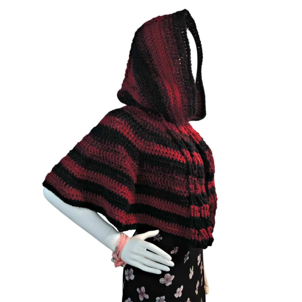 Red and black striped crochet hooded cape with cables down the back on a mannequin