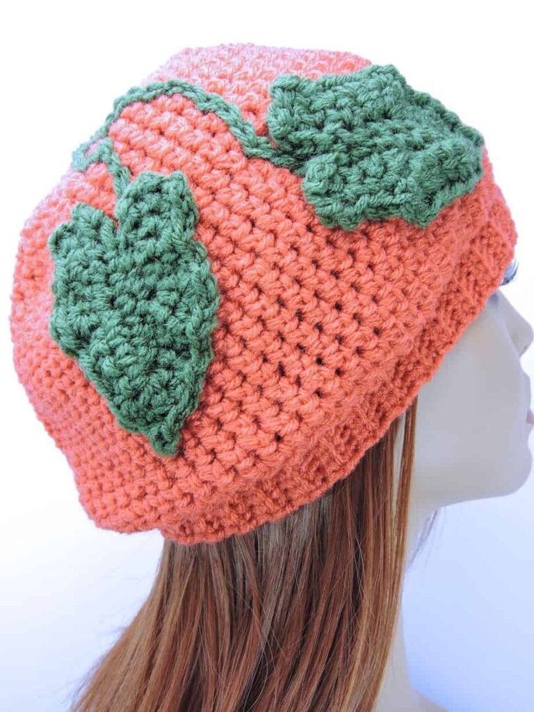 Coral slouchy crochet pumpkin hat with green leaves and chain stitch vines