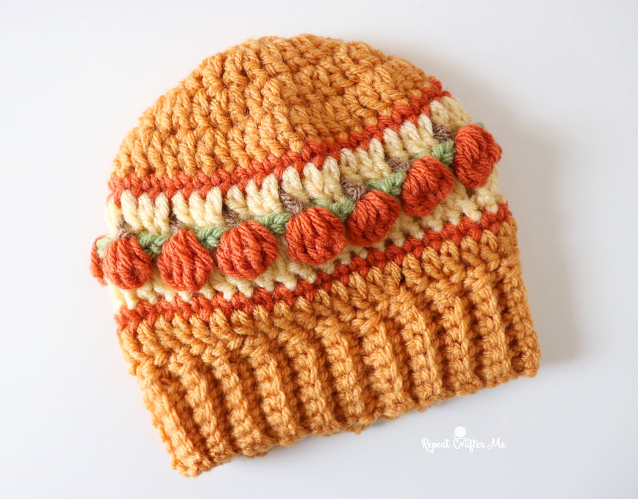 Orange crochet Halloween hat with a row of little pumpkins and a ribbed brim