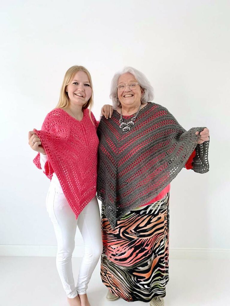 Two women wearing the Such Simple crochet poncho, one in pink and one in gray with red stripes