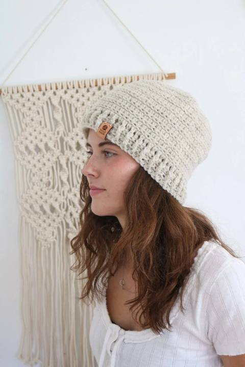 Woman wearing a cream reversible crochet beanie with a leather tag