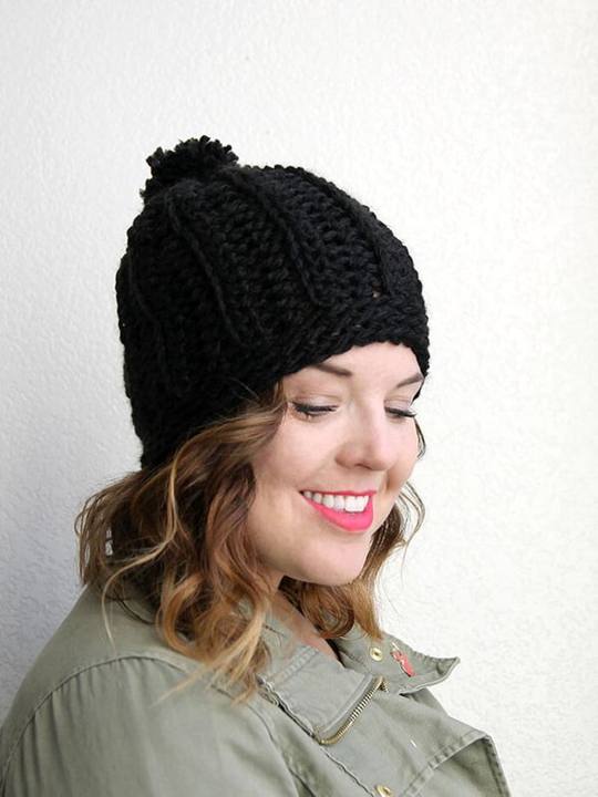 Woman wearing a black chunky ribbed slouch hat with a pom pom