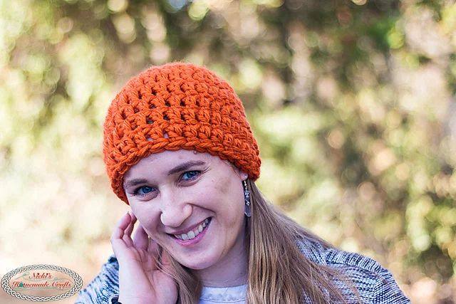 Free chunky crochet beanie pattern, a smiling woman wearing an orange chunky crochet beanie outdoors