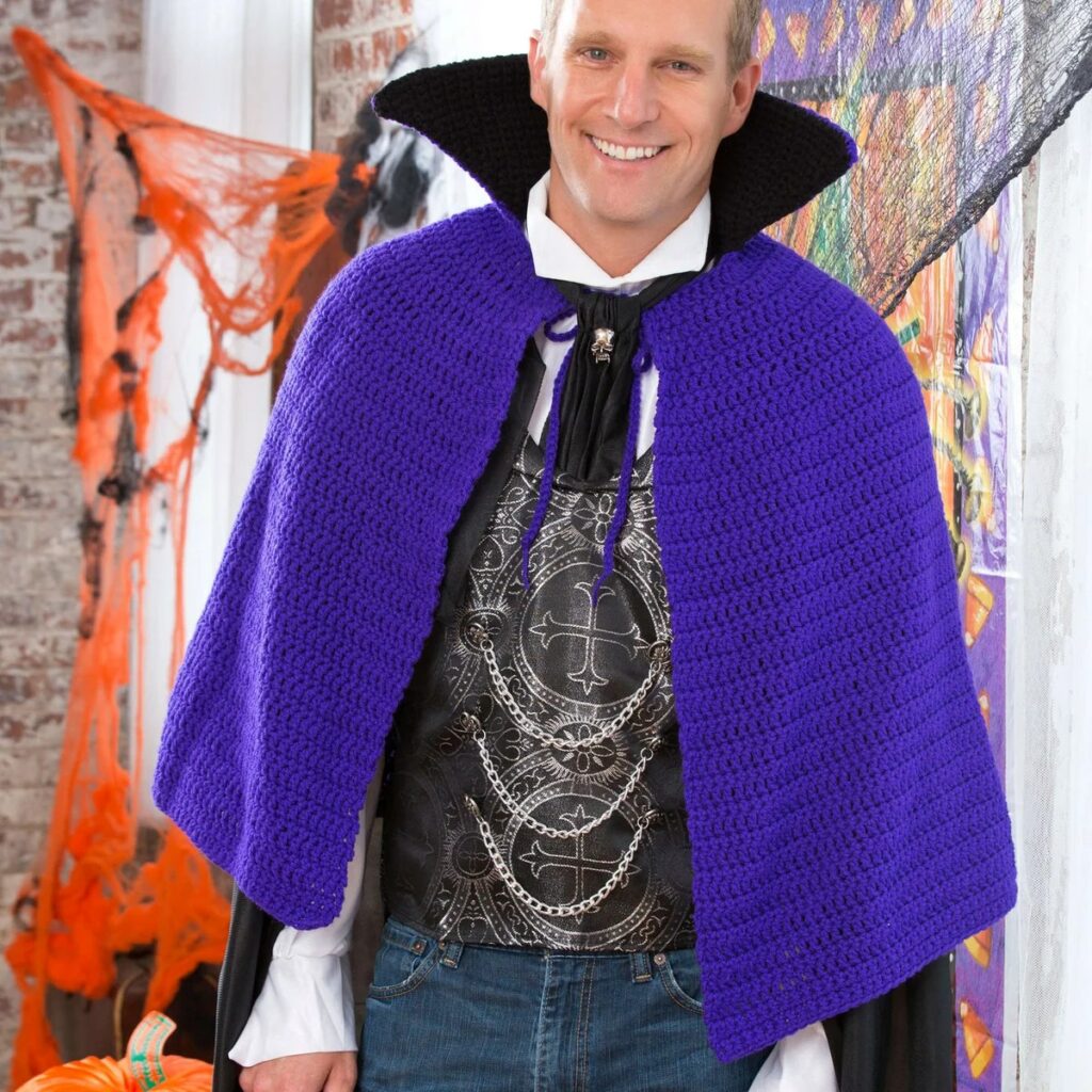 Man in a purple crochet vampire cape with a tall black stand-up collar, Halloween costume