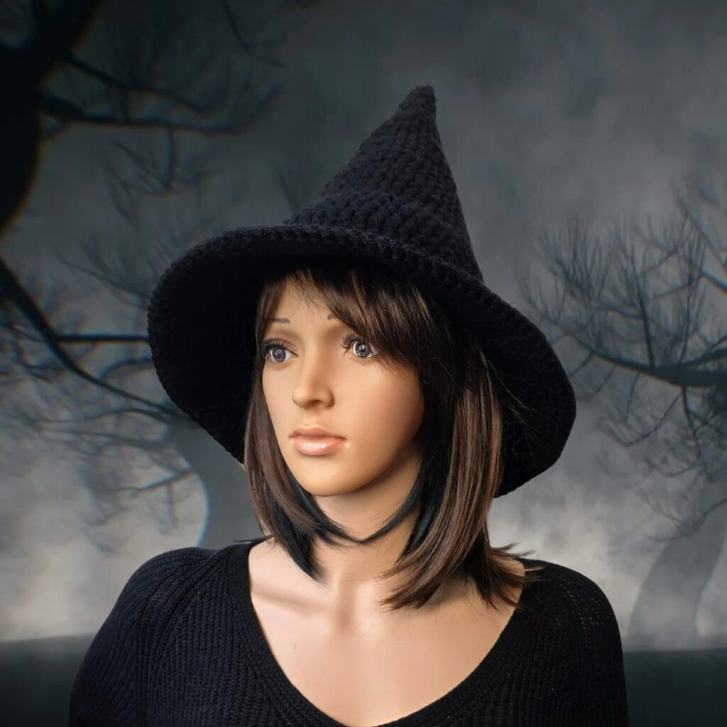 Black crochet witch hat with a tall pointed crown and wide brim on a mannequin, free Halloween costume pattern