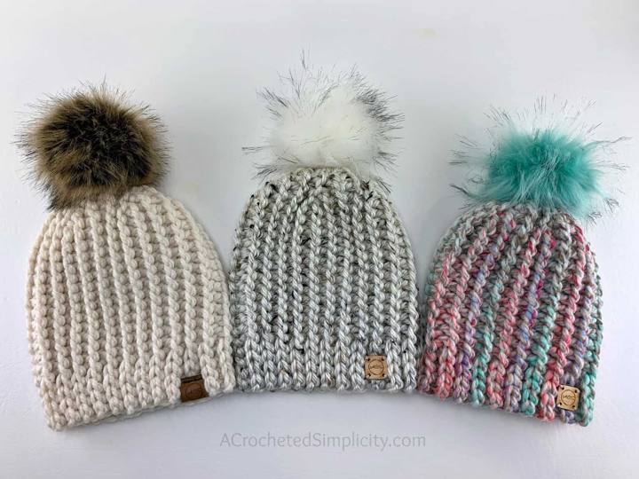 Three knit look crochet beanies in cream, gray and multicolor with faux fur pom poms