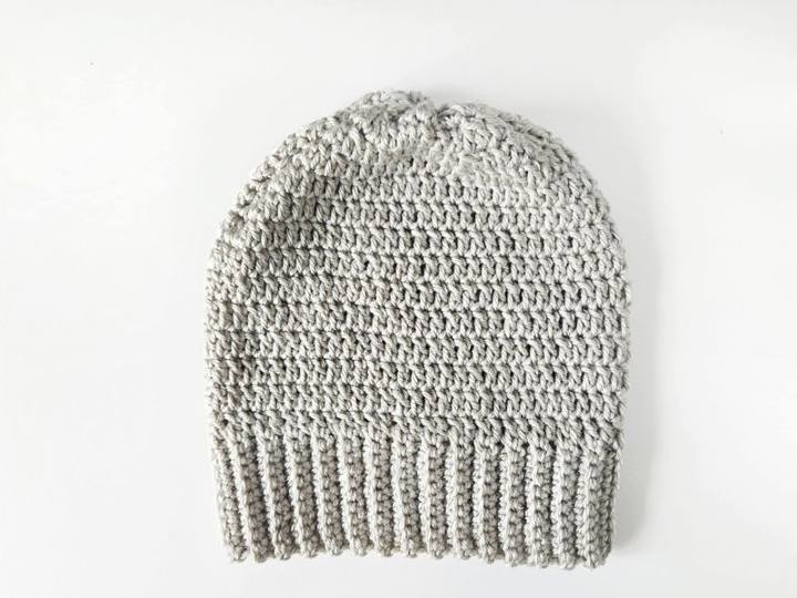Gray crochet hat with a ribbed brim lying flat